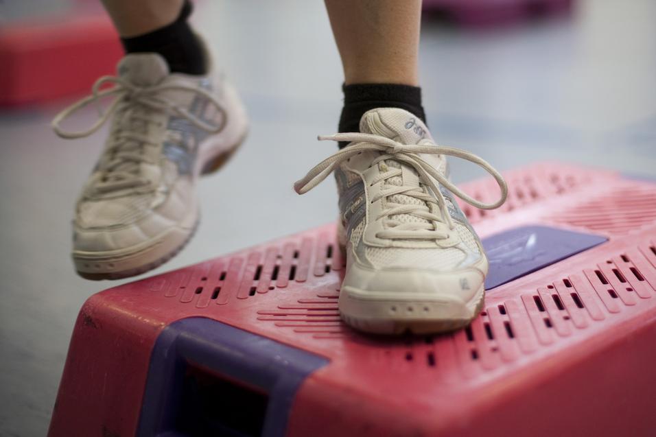 Nahaufnahme eines Sportschuhs auf einem pinken Stepper im Fitnessstudio.